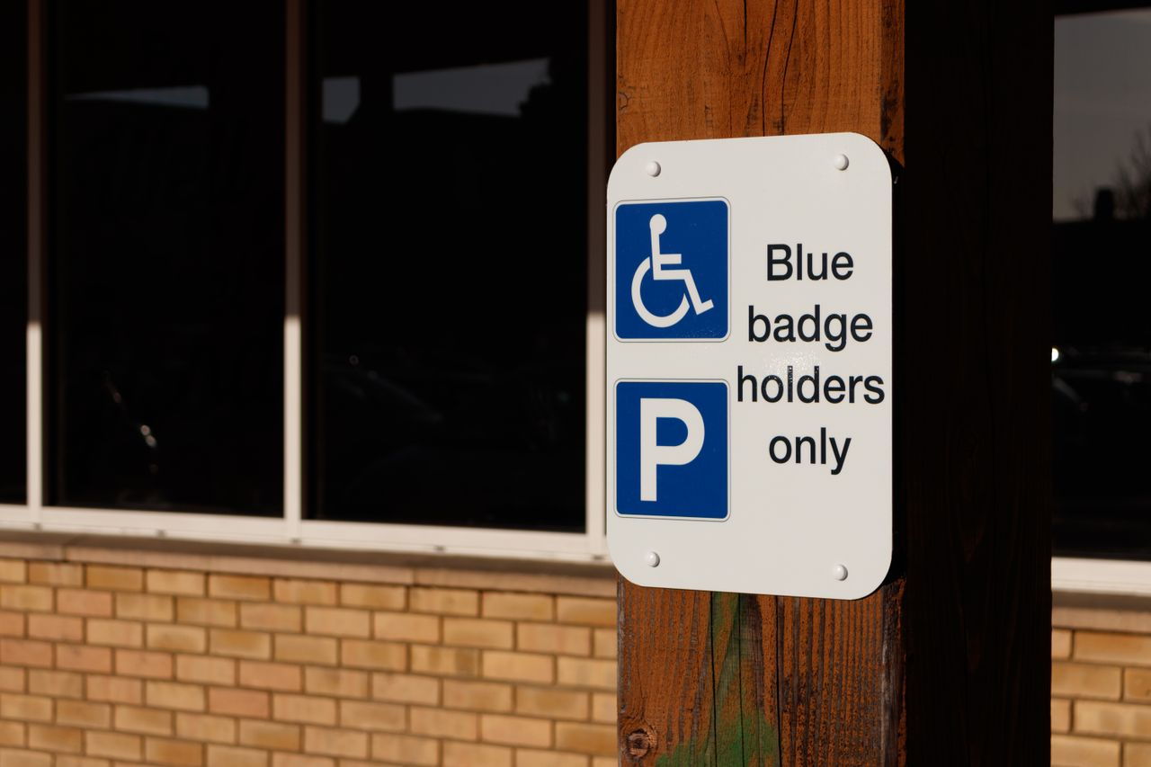 A sign indicating parking for blue badge holders only outside a building.