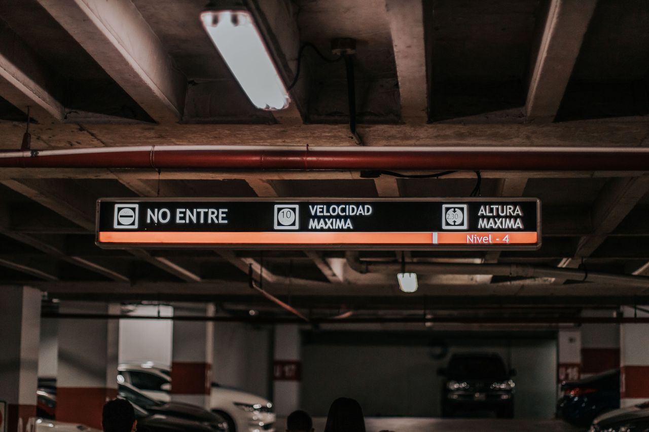 Interior view of a parking garage featuring overhead signage for vehicle height and speed limits.