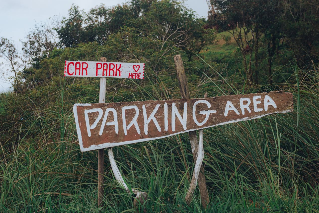 Handmade parking signs in a lush outdoor environment, guiding to car park.